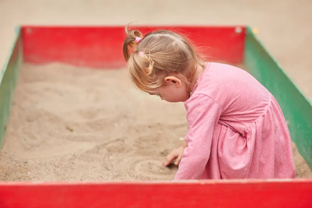 Child in a pink dress playing in sand box