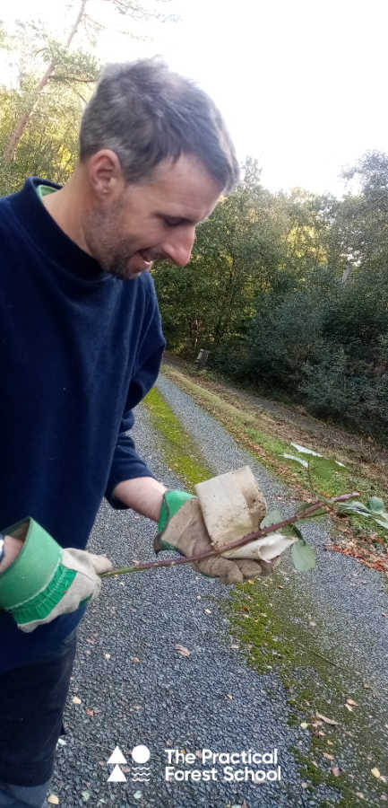 Jon is stripping the prickles off a bramble stem using gloves